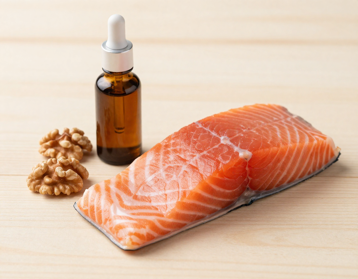 부드러운 나무 바닥 위 연어 필레와 생호두, 유리 스포이드 병이 놓인 실사 이미지.