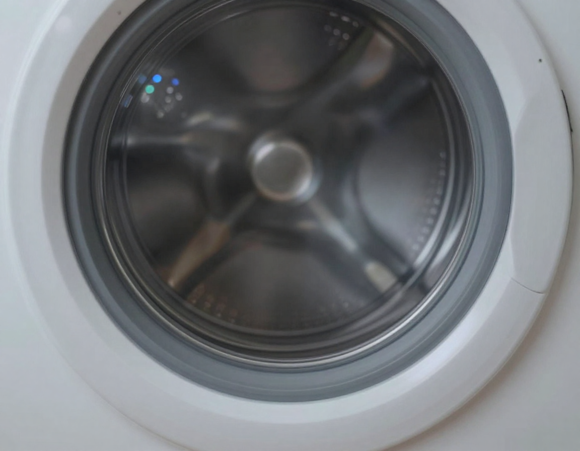은은한 스마트 조명이 반사되는 은색 세탁기 드럼 내부를 대각선 각도에서 촬영한 실사 이미지.