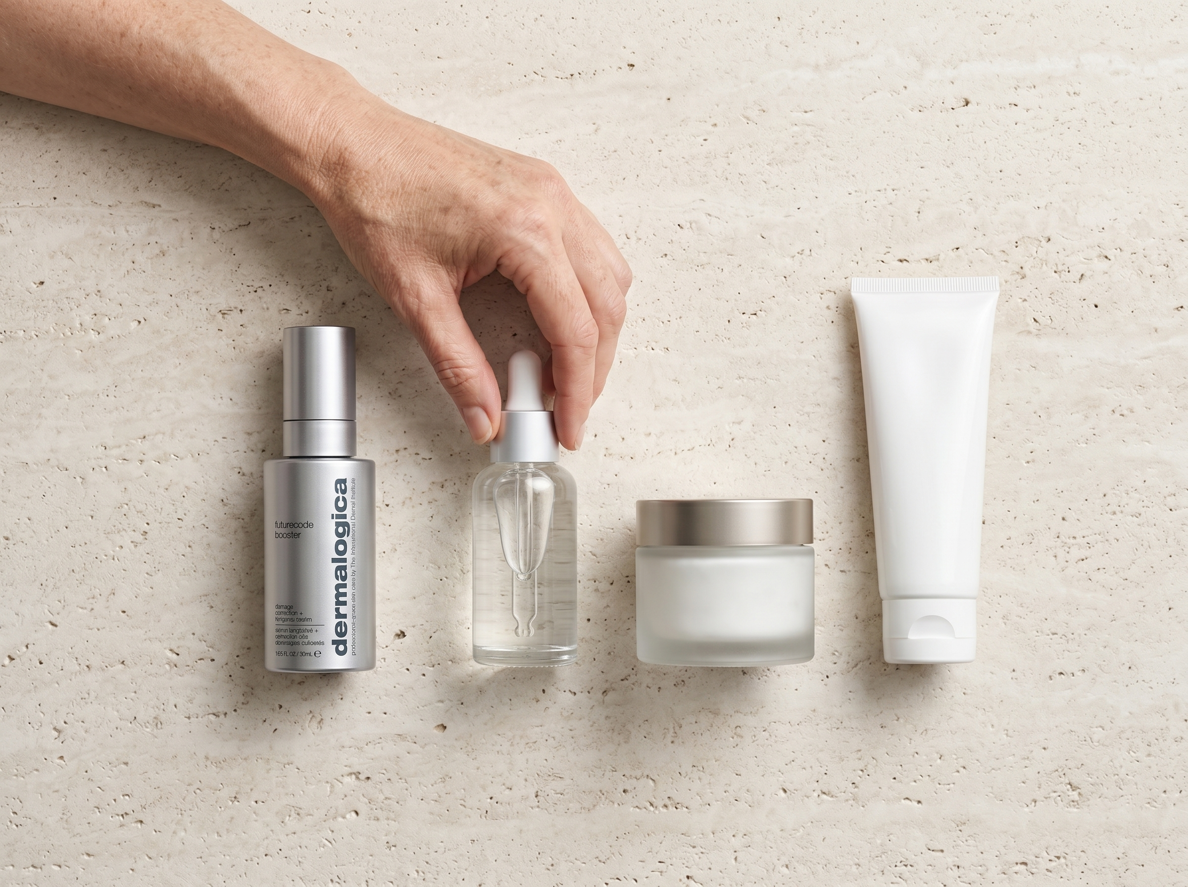 Flat lay of skincare products arranged in correct layering order from lightest to heaviest on a stone surface in natural light